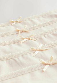 Svijetlosmeđi tkanina s mekim teksturom koja sadrži nekoliko delikatnih vrpci boje krem i čipkastu obrub duž šavova.