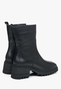 Zwarte leren enkellaarzen met een gladde afwerking, stevige rubberen zool en elastische zijkanten. Voorzien van een ronde neus en een lusje om aan te trekken.