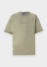 Olive green cotton t-shirt with short sleeves, round neck, and embossed "HUGO" logo on the front. Subtle texture and clean lines.