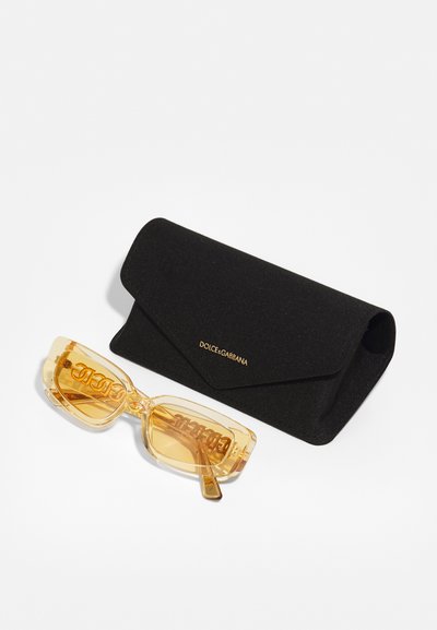 Yellow transparent sunglasses with bold "DOLCE&GABBANA" logo, accompanied by a black fabric case with a gold logo detail.