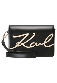 Černá kožená kabelka do ruky s výrazným zlatým podpisovým motivem. Má odnímatelný popruh a hladkou strukturu s minimem kovových prvků.