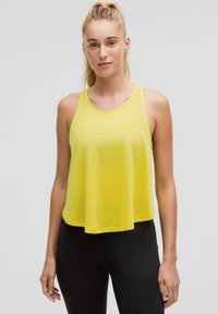 Geel mouwloos tanktop gemaakt van lichtgewicht stof, met een ronde halslijn en een losse pasvorm, gecombineerd met zwarte leggings.