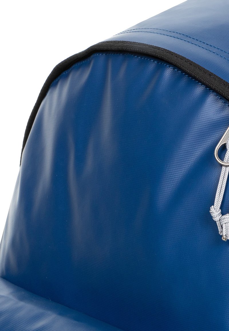 Tissu imperméable bleu avec une texture lisse, présente un bord noir et un clip argenté attaché par une corde gris clair. La forme est arrondie.