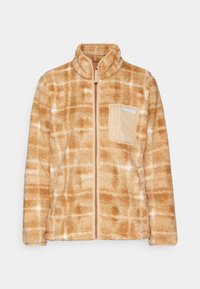 Veste en polaire beige avec un motif en quadrillage, dotée d'une fermeture éclair sur le devant et d'une poche sur la poitrine dans un beige plus clair avec un logo. Texture douce.