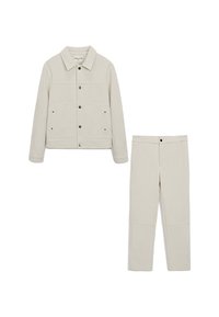 Veste en velours côtelé beige clair avec deux poches avant et des boutons-pression, assortie à un pantalon droit. Tissu lisse et texturé.