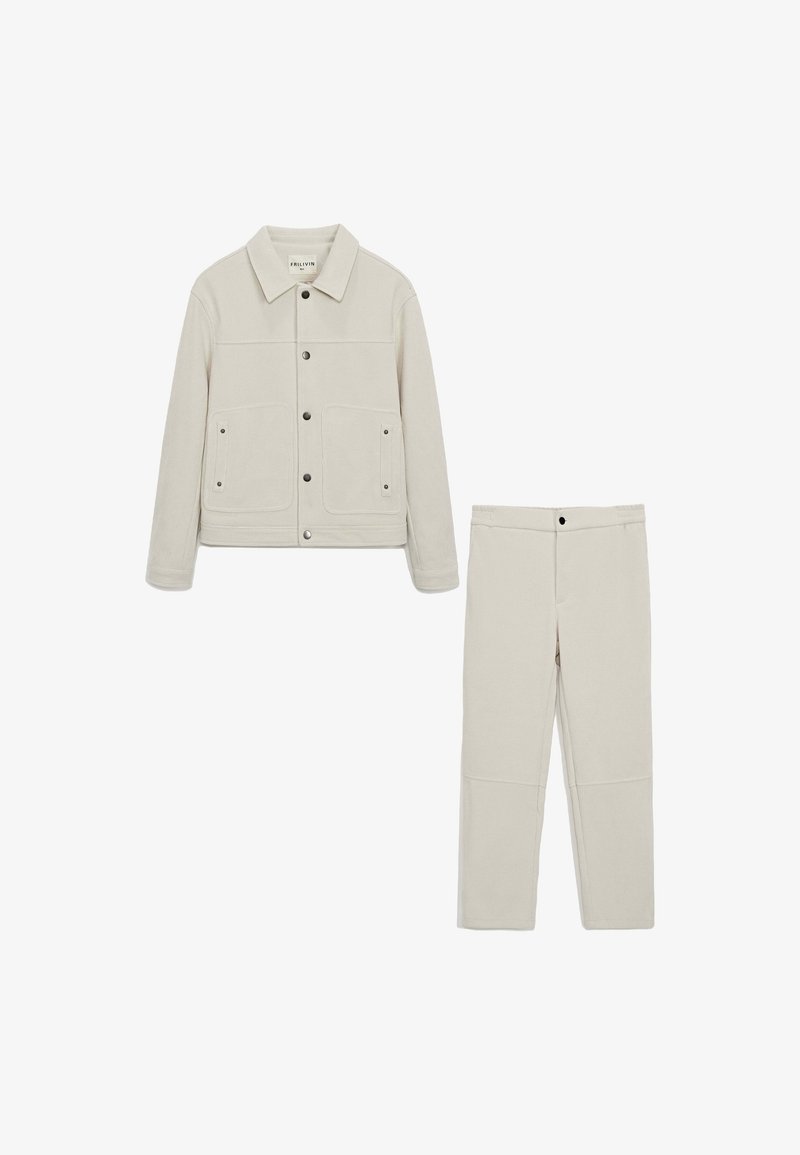 Veste en velours côtelé beige clair avec deux poches avant et des boutons-pression, assortie à un pantalon droit. Tissu lisse et texturé.