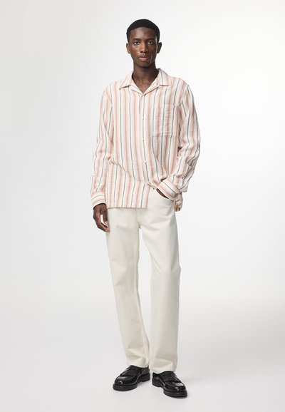 Stripet skjorte i lys pink, beige og orange, med brystlomme; parret med beige bukser og sorte sko. Glat stof tekstur.