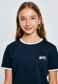 Jūras spēku T-krekls ar īsām piedurknēm un krējuma krāsas apdari. Uz krūtīm ir neliels, izšūts logotips gaiši rozā krāsā ar tekstu "BigStar 79".