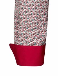 Cuff rosso di una camicia a fantasia con motivo a griglia in rosso, verde e bianco. Il tessuto ha una texture liscia.