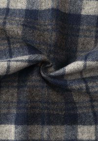 Tissu en laine avec un motif tartan bleu, gris et blanc, montrant une texture douce et un tissage complexe, avec un léger éclat.