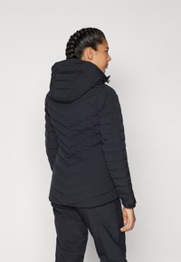 Black puffer jacket with a hood, featuring a quilted texture and chevron stitching pattern, designed for winter wear.