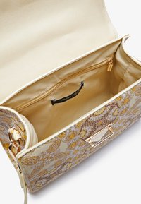 Blomstermønstret håndtaske i dæmpet gul og beige, med en glat tekstur, en guldfarvet lynlås og et mærket indvendigt label.