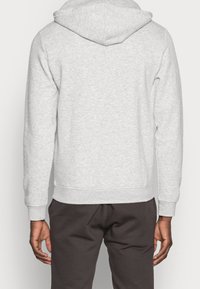 Grijze hoodie met een gestructureerde stof, elastische onderkant en manchetten. Zichtbare stikdetails op de naden.