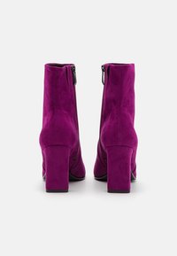 Botas de tobillo de ante fucsia con una textura suave, tacones altos de bloque y cremalleras laterales, que presentan un diseño de puntera redondeada.