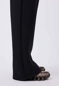 Zwarte sweatpants met een losse pasvorm, rechte pijpen en een zachte textuur. Gecombineerd met dikke, meerkleurige sneakers.