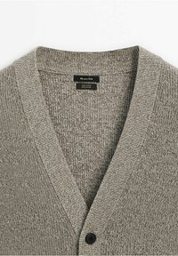 Cardigan gris tricoté en V avec un seul bouton noir, avec un col côtelé et un tissu texturé.