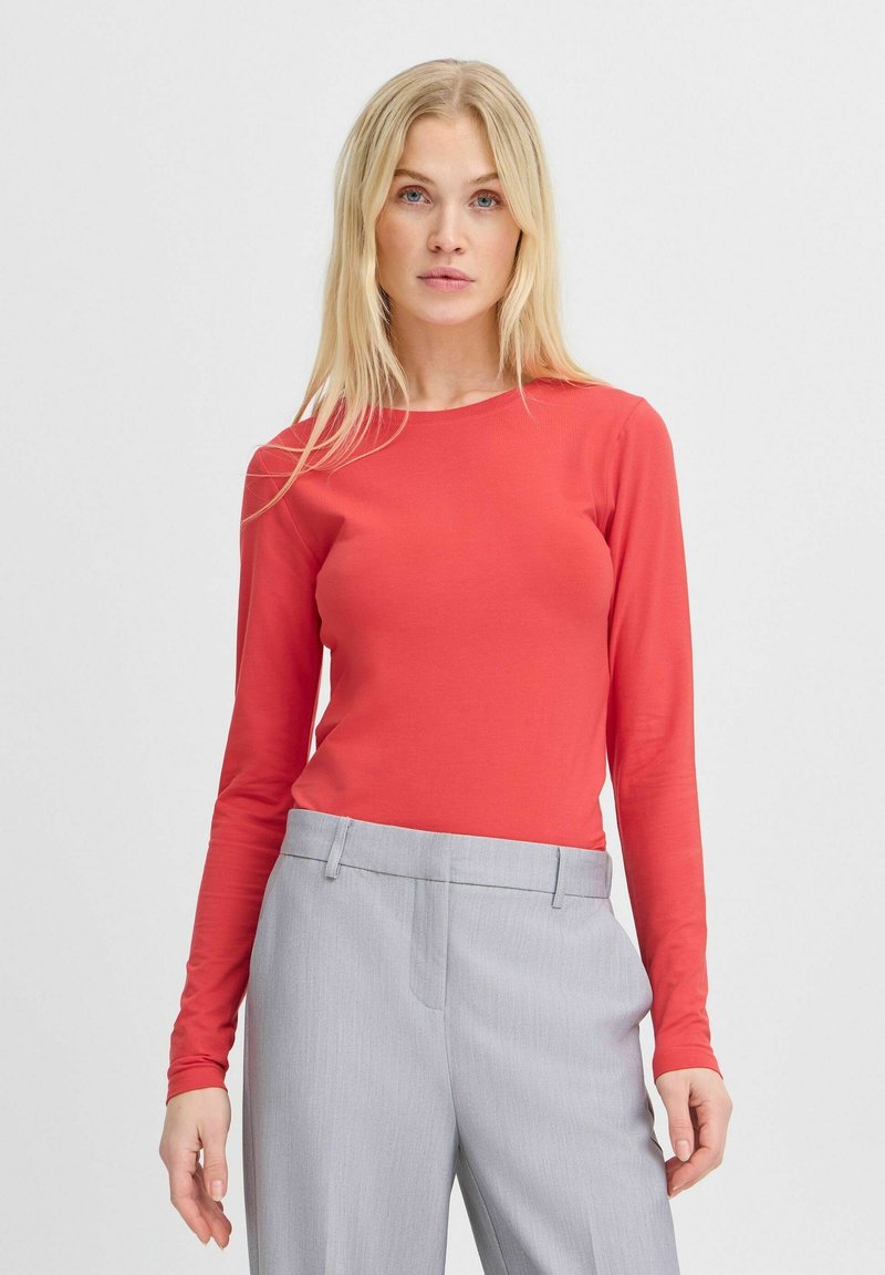 Pitkähihaista, korallinväristä slim fit -paitaa, joka on valmistettu sileästä kankaasta, jossa on ribbitetty rakenne. Yhdistetty vaaleanharmaisiin, räätälöityihin housuihin, joissa on sivutaskut.