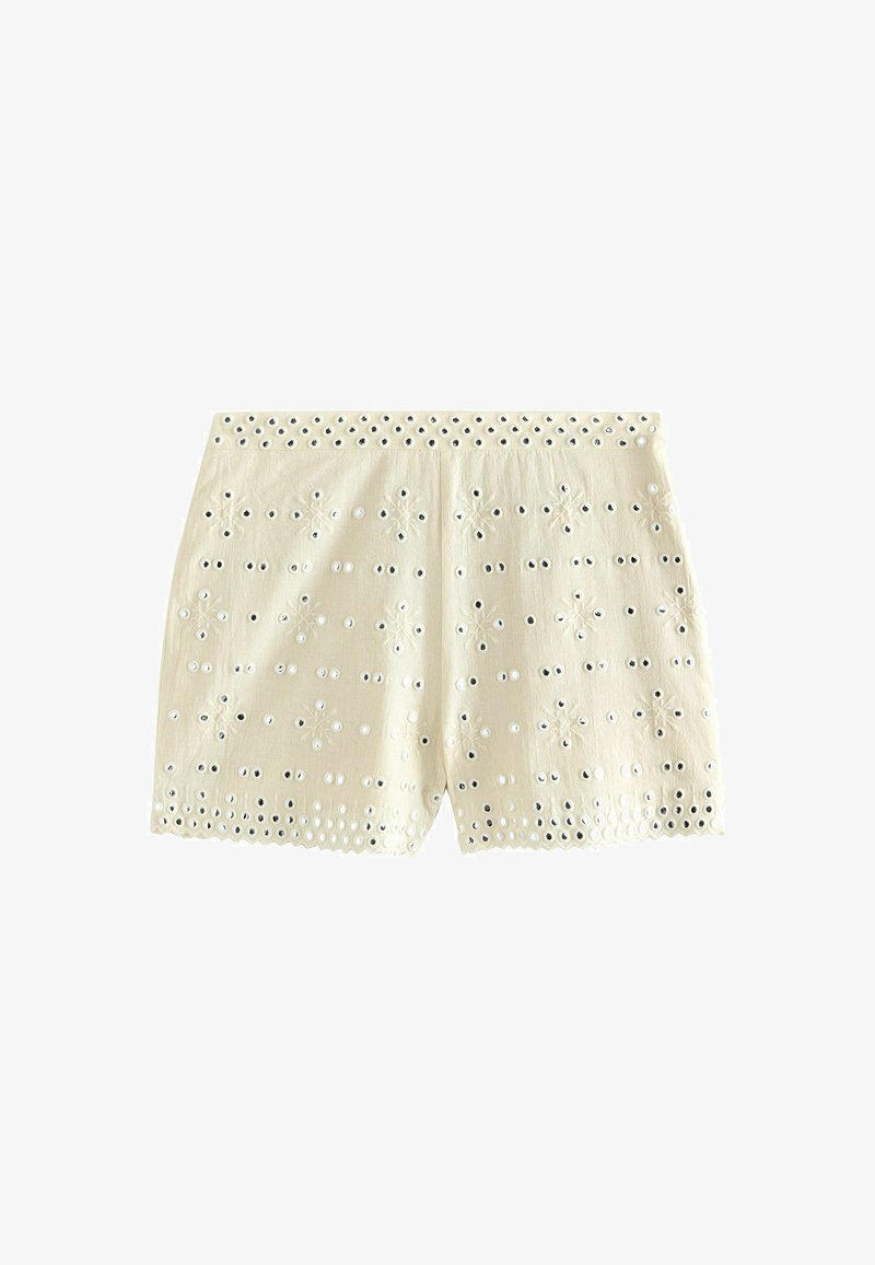 Shorts couleur crème avec broderie ajourée de motifs floraux et bords festonnés sur fond blanc.