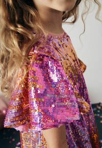 Robe pailletée avec un col rond, ornée de paillettes roses, violettes et dorées disposées en motif ondulé sur la poitrine et les manches.