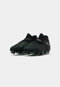 Black football boots with green accents, textured upper, sock-like collar, and black studded sole for traction on grass.