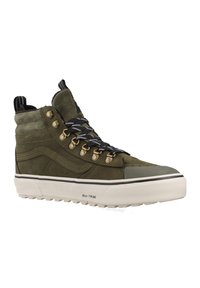 Zapatillas de deporte altas de color verde oliva con parte superior de ante, cordones en blanco y negro, ojales dorados, capuchón de goma en la punta y suela blanca texturizada.