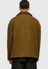 Veste en mélange de laine marron avec un large col, une coupe décontractée, des épaules tombantes et une texture lisse. Le design présente une coupe droite au niveau de l'ourlet.