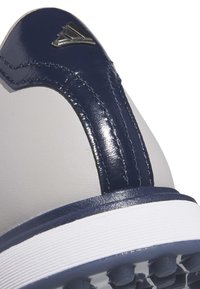 Šedé tenisky s námořnickým lakovaným koženým akcentem, elegantním designem, texturovanou boční panelem a bílou gumovou podrážkou s malými protiskluzovými nopky.