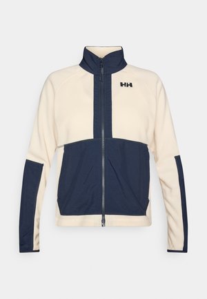 Veste en polaire avec un corps crème et des accents bleu marine, col montant et fermeture éclair intégrale à l'avant. Logo brodé sur la poitrine.