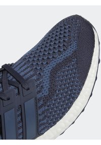 Gros plan d'une chaussure de sport en tricot bleu marine avec des lacets noirs et une semelle blanche rembourrée.