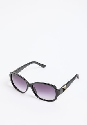 Crne pravokutne sunčane naočale s gradijent ljubičastim lećama i zlatnim detaljima na kracima, odložene na bijeloj površini.