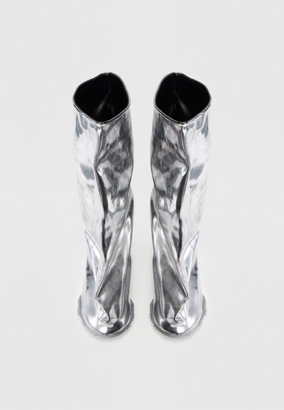 Bottes argentées jusqu'aux genoux avec une texture lisse et froissée ; intérieur noir lisse ; semelles arrondies et texturées pour une meilleure adhérence.