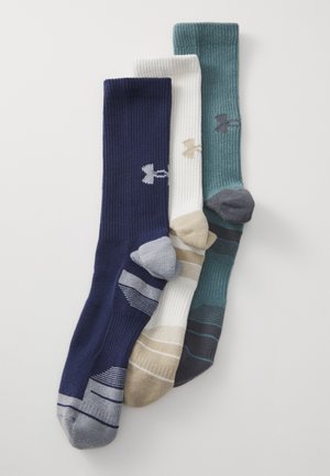 Tre paia di calzini a coste: blu navy, crema e teal, con strisce a fantasia contrastanti e piccoli dettagli del logo su ciascuno.