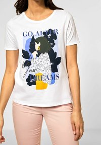 Bílý bavlněný tričko s grafikou ženy v živých barvách, s nápisem "Jdi za svými sny" a krátkým rukávem.