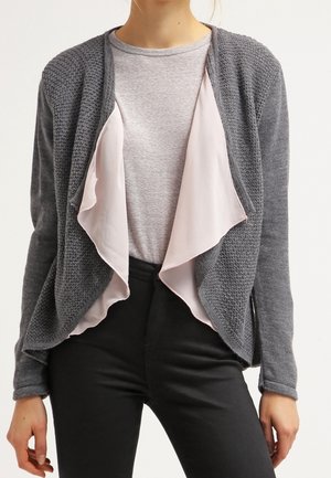 Cardigan grigio lavorato a maglia con uno strato interno in satin rosa, design aperto sul davanti, maniche lunghe e superficie testurizzata. Abbinato a una t-shirt grigia.