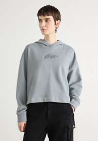 Lys grå cropped hettegenser med en avslappet passform, med snorhette og dekorativ rhinsteinbokstav på brystet.