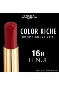 Rouge à lèvres mat rouge dans un tube doré avec un dessus arrondi. L'étiquette comprend le nom de la marque, la ligne de produit, la durée et le numéro de la teinte.