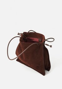 Borsa in suede marrone con forma triangolare, texture morbida e manici in pelle marrone. L'interno ha una fodera rossa a contrasto.