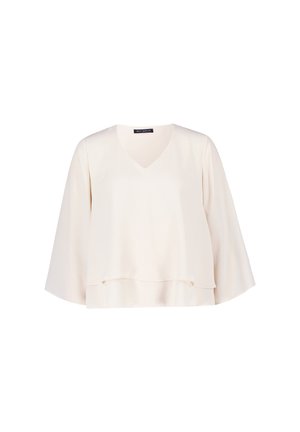 Top di crema chiaro con scollatura a V, maniche ampie e orlo a strati. Realizzato in un tessuto morbido con una silhouette leggermente drappeggiata.