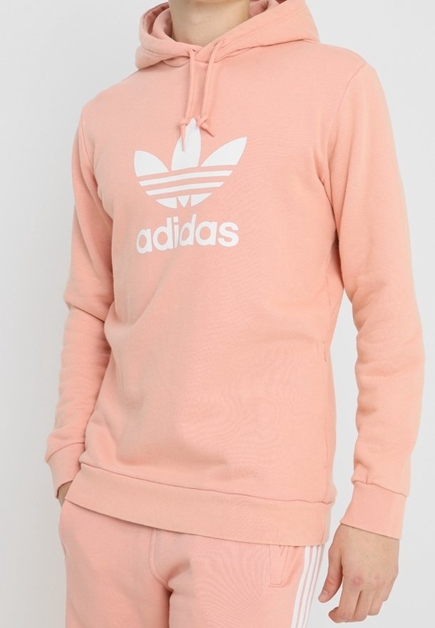 Felpa leggera rosa chiaro in misto cotone, con un grande logo Adidas bianco e tre strisce bianche sulle maniche. Include cappuccio con cordino.