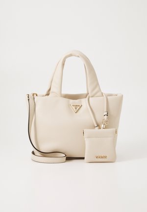 Sac à main en cuir beige doux avec des poignées rembourrées, une bandoulière amovible et une petite pochette attachée, ornée de logos Guess dorés.