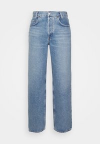 Jean bleu clair taille haute, jambe droite, avec poches avant, fermeture par boutons et passants de ceinture sur fond blanc.