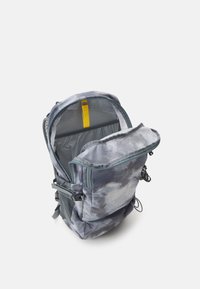 Mochila con un diseño de nubes en azul y gris, que incluye un interior gris, correas ajustables y un acento amarillo en la apertura superior.