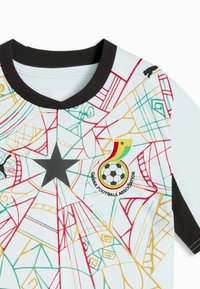 Maillot de football blanc avec col et bordures de manches noires, motif géométrique coloré, étoile noire et logo de l'Association de football du Ghana avec ballon de football.