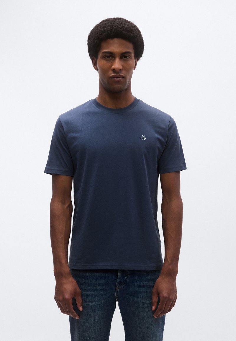 Granatowy bawełniany t-shirt z okrągłym dekoltem i krótkimi rękawami, z małym logo na lewej stronie klatki piersiowej. Luźny fason i gładka faktura.