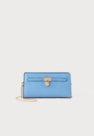 Blå læderpung med en gylden låse detalje, rektangulær form og kædesnor. Har en tekstureret overflade og en svagt kontrasterende kant.