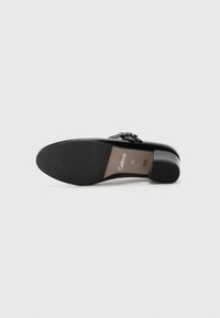 Chaussure à talon haut noire avec une surface lisse, ornée d'une boucle décorative et d'une semelle en caoutchouc texturée. Étiquette de taille visible.