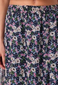Jupe à motif floral avec un fond bleu marine, ornée de fleurs roses, blanches et vertes. Ceinture élastique ; tissu léger et texturé.