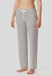 Pantalones de dormir ligeros y estampados en blanco con un diseño geométrico en negro y rosa, que cuentan con una cintura con cordón ajustable y piernas rectas.