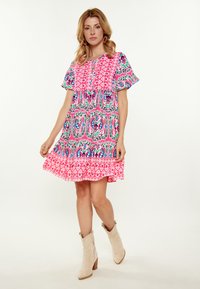 Abito A-line multicolore con vivaci motivi rosa, blu e verdi; maniche corte; scollo rotondo; orlo fluente.