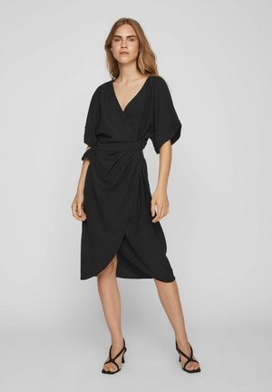 Robe noire enveloppante avec un décolleté en V profond, des manches kimono courtes et un lien sur le côté. Fabriquée en tissu texturé avec un ourlet au genou.